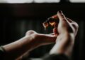 person holding amber glass bottle